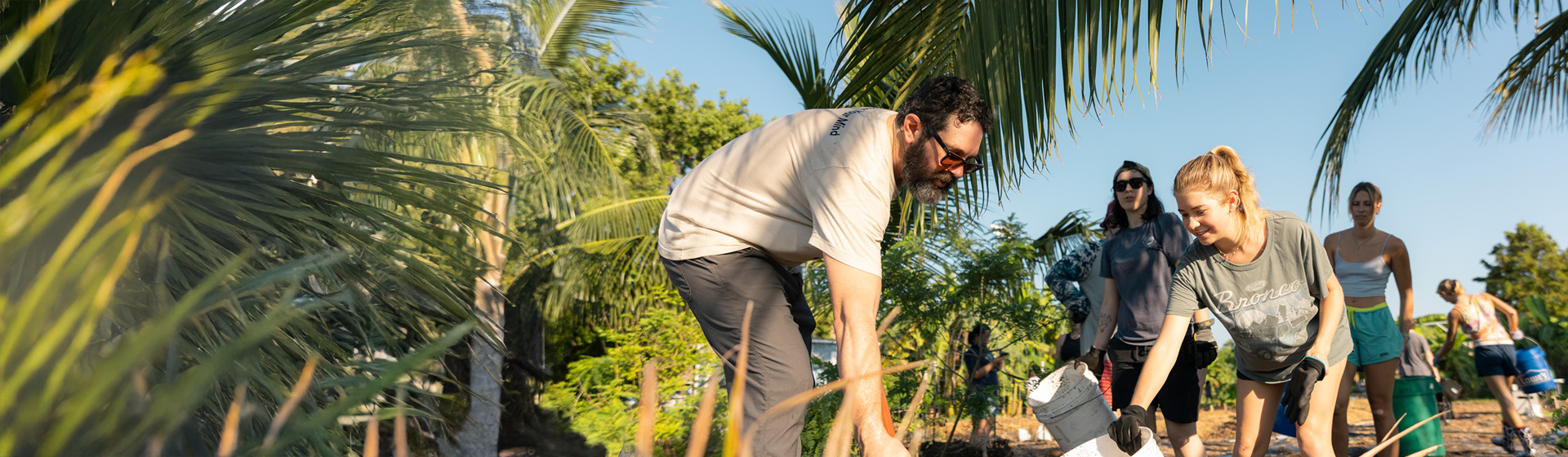 Students and professor wear gloves while working on a farm