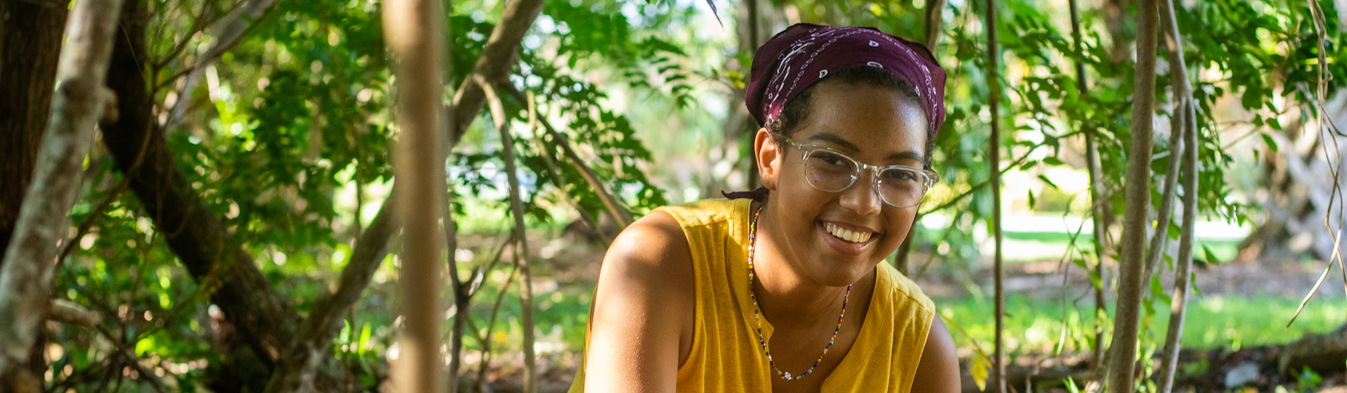 Student wearing glasses squats in the mangroves